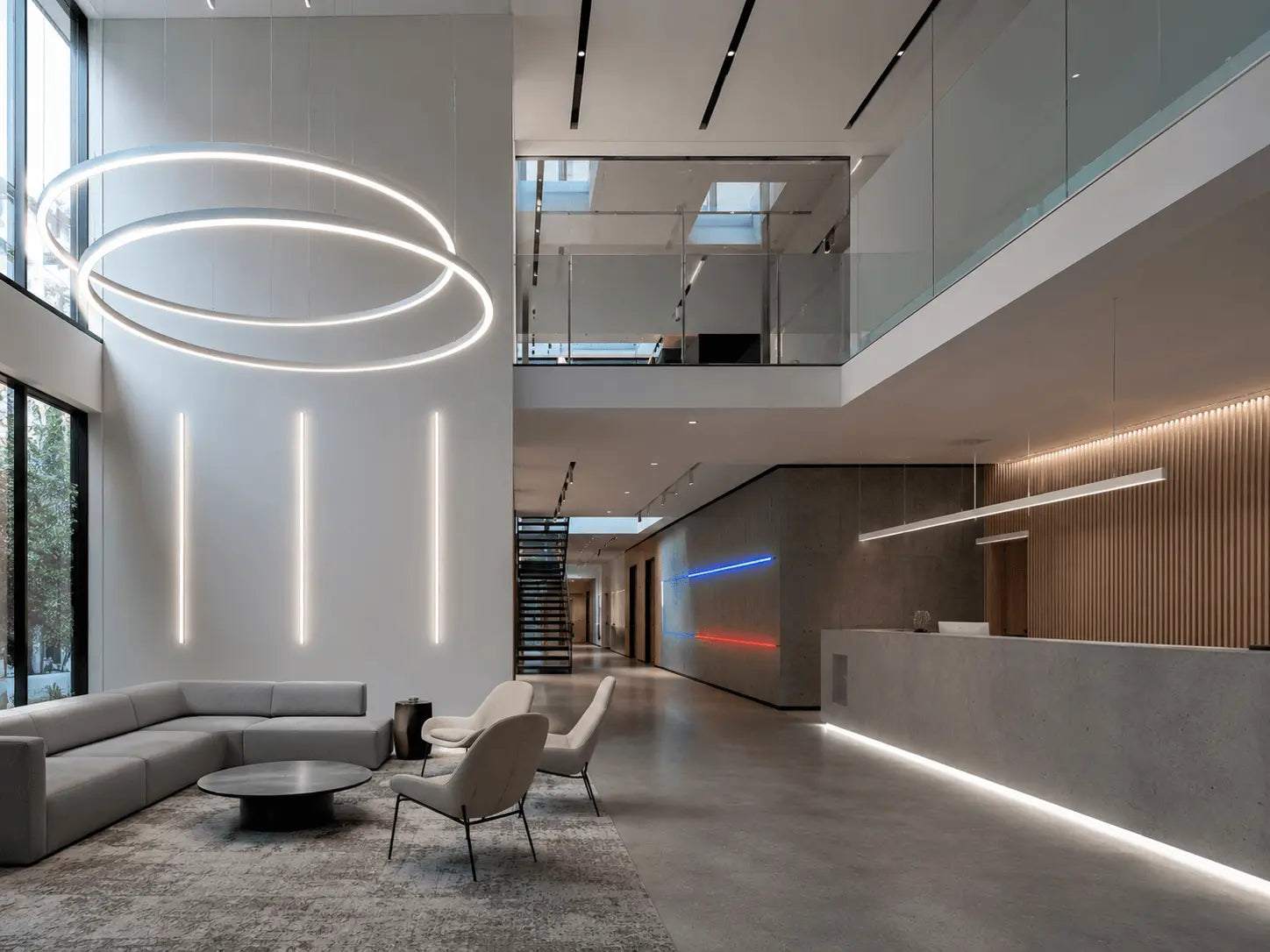 Modern interior design of a lobby with circular light fixture, gray sofa, and glass walls.